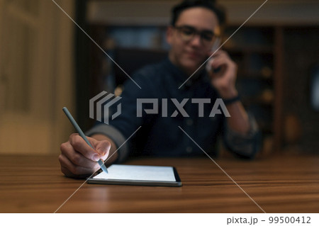 Young man wearing glasses graphic designer working late at night 99500412
