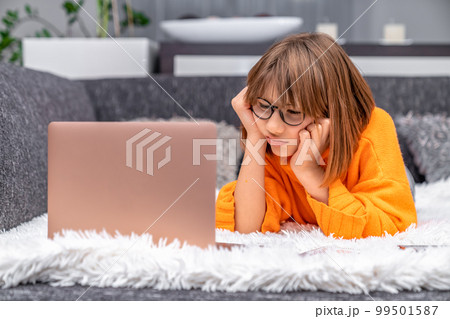 disappointed kid looking at laptop at home on sofa disappointed kid looking at laptop at home on sofa 99501587