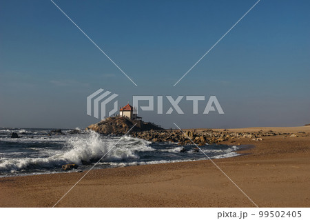 Beautiful Miramar beach, seashore at sunset. Golden Atlantic ocean coast with waves. Old Portuguese chapel Senhor da Pedra near Porto town. Oporto district, Portugal. Travel Europe concept. Blue sky. Beautiful Miramar beach, seashore at sunset. Golden Atlantic ocean coast with waves. Old Portuguese chapel Senhor da Pedra near Porto town. Oporto district, Portugal. Travel Europe concept. Blue sky. 99502405