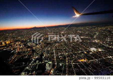 飛行機の窓の外から観る夕焼けと富士山と東京の夜景 99503110