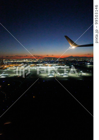 飛行機の窓の外から観る夕焼けと富士山と東京の夜景 99503146