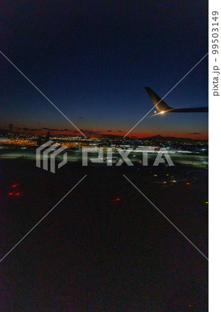 飛行機の窓の外から観る夕焼けと富士山と東京の夜景 99503149