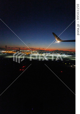 飛行機の窓の外から観る夕焼けと富士山と東京の夜景 99503150
