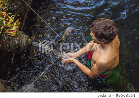 Man in holy spring water temple in bali. The temple compound consists of a petirtaan or bathing structure, famous for its holy spring water 99503551