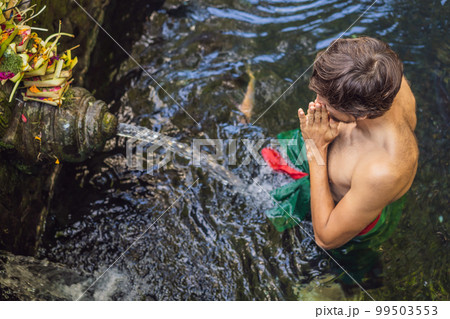 Man in holy spring water temple in bali. The temple compound consists of a petirtaan or bathing structure, famous for its holy spring water 99503553