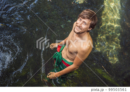 Man in holy spring water temple in bali. The temple compound consists of a petirtaan or bathing structure, famous for its holy spring water Man in holy spring water temple in bali. The temple compound consists of a petirtaan or bathing structure, famous for its holy spring water 99503561