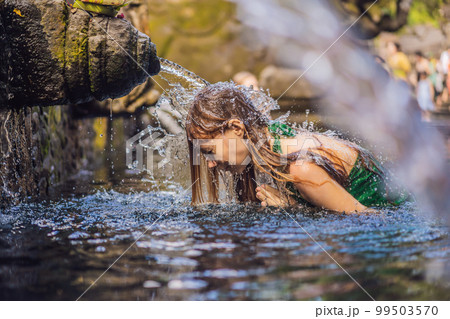 Woman in holy spring water temple in bali. The temple compound consists of a petirtaan or bathing structure, famous for its holy spring water 99503570