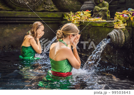 Two women in holy spring water temple in bali. The temple compound consists of a petirtaan or bathing structure, famous for its holy spring water 99503643