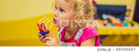 happy child girl laughing and playing with toys constructor BANNER, LONG FORMAT 99504047