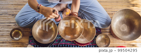 BANNER, LONG FORMAT Nepal Buddha copper singing bowl at spa salon. Young beautiful woman doing massage therapy singing bowls in the Spa against a waterfall. Sound therapy, recreation, meditation 99504295