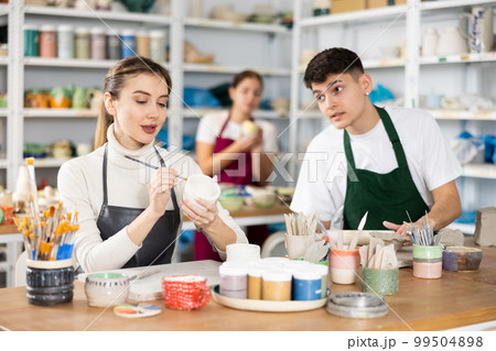 Young woman and young man making pottery Young woman and young man making pottery 99504898
