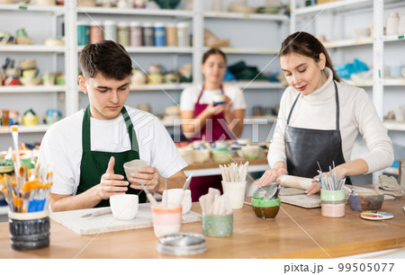 Young woman and young man making pottery 99505077