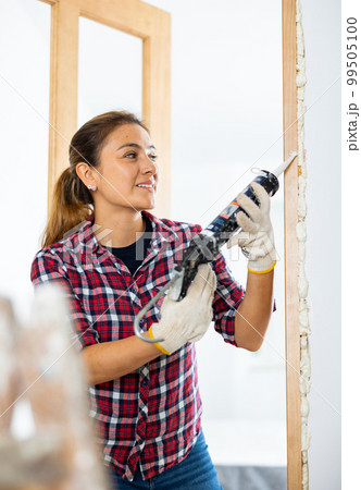 Cheerful woman using spray foam Cheerful woman using spray foam 99505100