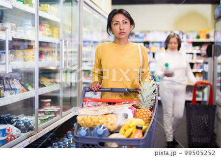 Woman shopping at store, walking among shelves Woman shopping at store, walking among shelves 99505252