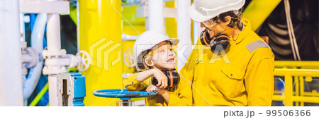 BANNER, LONG FORMAT Young man and a little boy are both in a yellow work uniform, glasses, and helmet in an industrial environment, oil Platform or liquefied gas plant 99506366