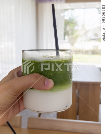 Hand holding iced matcha green tea Hand holding iced matcha green tea 99506583