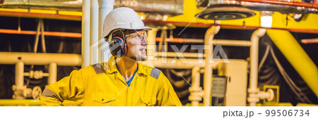 Young man in a yellow work uniform, glasses and helmet in industrial environment,oil Platform or liquefied gas plant BANNER, LONG FORMAT Young man in a yellow work uniform, glasses and helmet in industrial environment,oil Platform or liquefied gas plant BANNER, LONG FORMAT 99506734