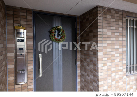 玄関にクリスマスリースを飾る 99507144
