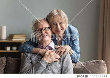 Positive happy elderly couple of married pensioners, grandparents home portrait Positive happy elderly couple of married pensioners, grandparents home portrait 99507541