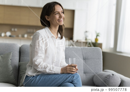 Positive cheerful young woman holding glass of pure natural water Positive cheerful young woman holding glass of pure natural water 99507778