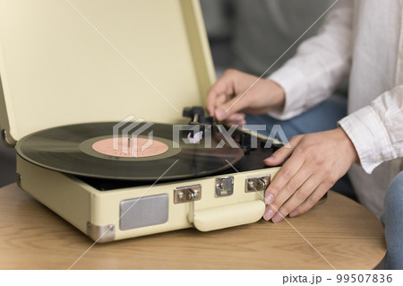 DJ woman starting retro player with needle on vinyl plate 99507836