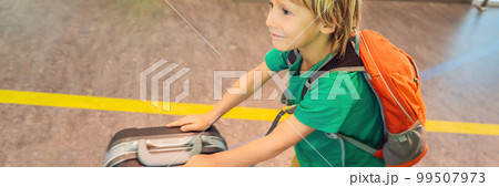 Funny little boy going on vacations trip with suitcase at airport, indoors BANNER, LONG FORMAT 99507973