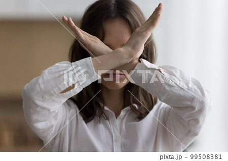 Serious young woman showing crossed arms at camera 99508381