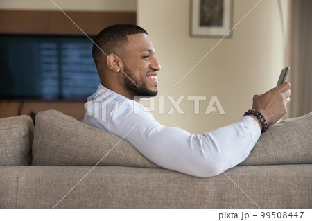 Cheerful excited handsome Black guy using mobile phone 99508447