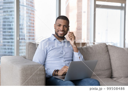 Cheerful busy handsome millennial freelance entrepreneur talking on mobile phone Cheerful busy handsome millennial freelance entrepreneur talking on mobile phone 99508486
