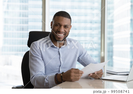 Excited African business man holding legal documents at office table 99508741