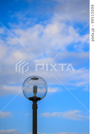 青い空と白い雲が街灯のガラスの中に写しこむ 99515099