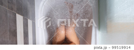 Naked woman sits in bathtub under shower top view Naked woman sits in bathtub under shower top view 99519914