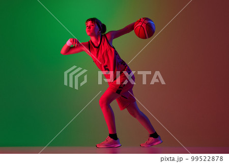 Teen girl, basketball player in motion with ball isolated over gradient green red background in neon light. Concept of professional sport and hobby Teen girl, basketball player in motion with ball isolated over gradient green red background in neon light. Concept of professional sport and hobby 99522878