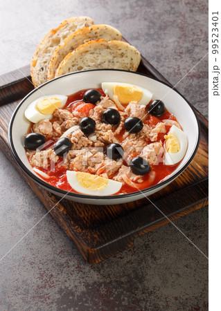Murcian salad or mojete, a traditional fresh and light recipe that is prepared with tomato, canned tuna, black olive, egg and onion closeup on the plate. Vertical 99523401