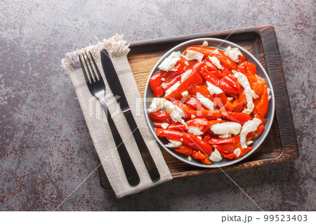 Esgarraet is a typical dish from the Valencian community in Spain it consists of grilled red pepper salad, cured cod, garlic, olive oil closeup. Horizontal top view 99523403