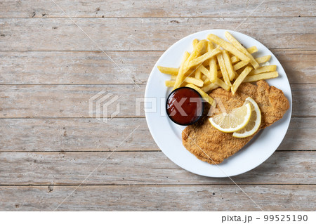 Wiener schnitzel with fried potatoes on wooedn table Wiener schnitzel with fried potatoes on wooedn table 99525190