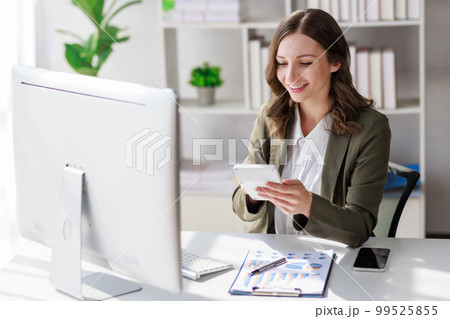 Concept of business investment or working woman, Businesswoman wearing a suit sitting and working on analysis of business investment documents and using calculator to analytic business data. Concept of business investment or working woman, Businesswoman wearing a suit sitting and working on analysis of business investment documents and using calculator to analytic business data. 99525855