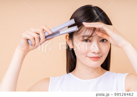 ヘアアイロンをする若い女性 99526462