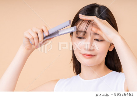 ヘアアイロンをする若い女性 99526463