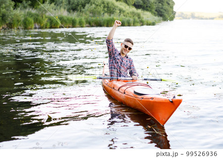 Adult caucasian man is sitting in a kayak and greetings. The concept of the water activities. Adult caucasian man is sitting in a kayak and greetings. The concept of the water activities. 99526936