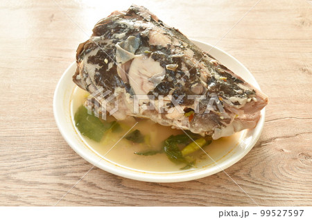 boiled Asian Redtail catfish head with chili and lemon dressings celery tom yum soup on plate 99527597