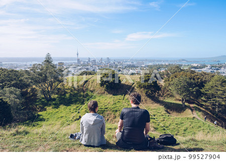 The young couple take a holiday time on the summit of mount Eden for seeing panorama view of Auckland town, North Island, New Zealand. The young couple take a holiday time on the summit of mount Eden for seeing panorama view of Auckland town, North Island, New Zealand. 99527904