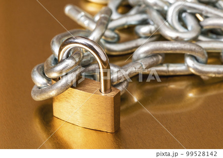 Yellow padlock with a pile of metal chain 99528142