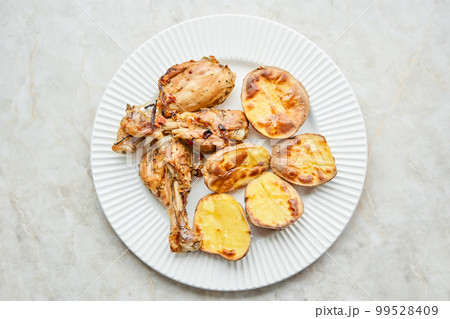 Chicken baked in pieces with potatoes and onion on a white dish. Home cooking. Healthy food, cooked without oil and salt. 99528409