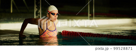 Winner. Young woman, professional female swimming athlete in cap and goggles posing in pool indoor. Success. Concept of sport, endurance, competition Winner. Young woman, professional female swimming athlete in cap and goggles posing in pool indoor. Success. Concept of sport, endurance, competition 99528871