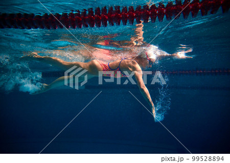 Coordinated movements, speed. Professional female swimmer training in swimming pool indoor. Underwater view. Concept of sport, endurance, competition 99528894