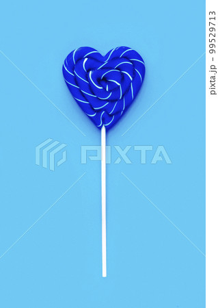 Classic Blue color of the Year 2020. Blue lollipop heart shaped on blue background. Candy. Love and sweet concept. Valentine day. Classic Blue color of the Year 2020. Blue lollipop heart shaped on blue background. Candy. Love and sweet concept. Valentine day. 99529713