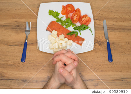 A man prays before meal. Hands close-up. Healthy food. Keto diet. Selective focus. A man prays before meal. Hands close-up. Healthy food. Keto diet. Selective focus. 99529959