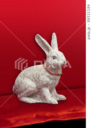 side view white rabbit statue wearing a red thread and amulets on red velvet fabric floor, red wall background, object, animal, decor, antique, ancient, copy space side view white rabbit statue wearing a red thread and amulets on red velvet fabric floor, red wall background, object, animal, decor, antique, ancient, copy space 99531184
