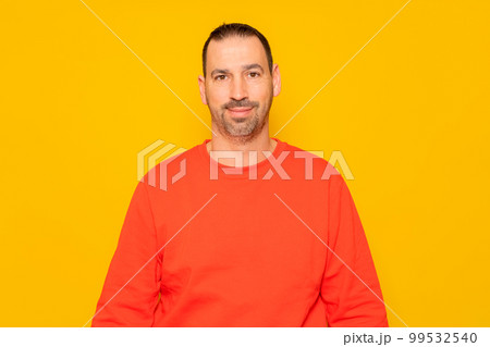 Isolated photo of a handsome man with a beard, wears a casual red sweater. He has a cheerful and relaxed expression, he is happy and content with his life 99532540